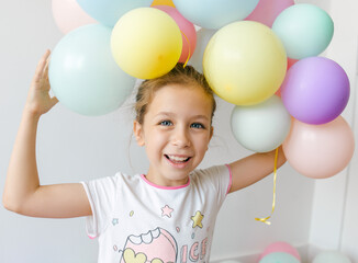 A little happy  girl with colorful balloons on a white background, studio shoot. Celebrations, birthday and playing concept.