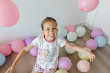 A little happy  girl with colorful balloons on a white background, studio shoot. Celebrations, birthday and playing concept. Top view