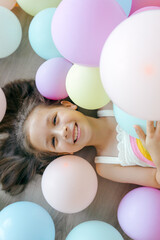 A little happy  girl with colorful balloons on a white background, studio shoot. Celebrations, birthday and playing concept. Top view