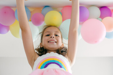 A beautiful little girl with colorful balloons in pastel colors on a white background. Celebration, birthday, party, childhood concept