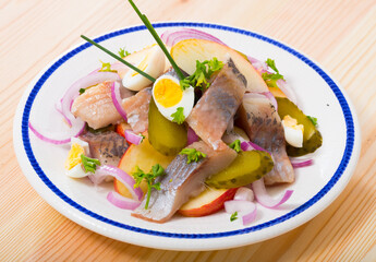 Marinated herring with sliced apples, cucumbers, onion - traditional dish of Norwegian cuisine