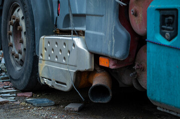 Fototapeta premium A large truck with visible wear parked at a construction site, highlighting its exhaust system in the late afternoon light