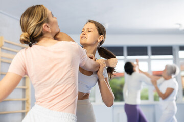 Women train during krav maga training session and work out basic elements with partner. Martial arts school, melee