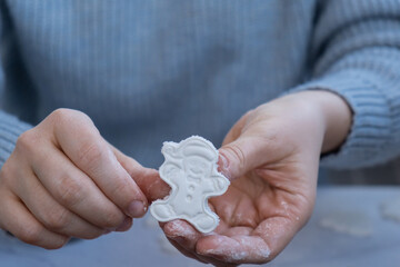Gingerbread character Creator is using white air dry clay for making decor to Christmas tree holiday. Creating hobby recreation activity that involves fingers. DIY crafting Modern art 