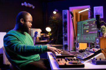 Modern producer playing piano keys to record a new soundtrack, trying to produce a song using midi...