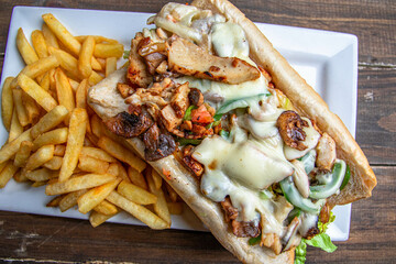 grilled chicken sub sandwich with side of French fries and topped with tasty melted cheese and grilled pepper.