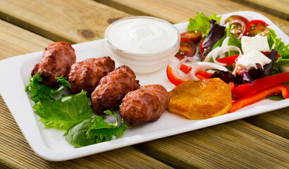 Balkan dish of minced meat kebapcheta served with salad of greens and brynza