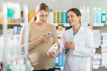 Pregnant woman in pharmacy scans QR code on antifungal cream product, checks certificate on...