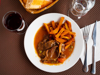 Delicious beef stew served in sauce with baked potatoes on plate