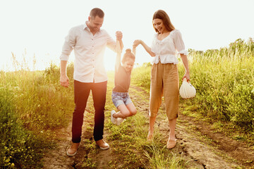 Fototapeta premium Sincere Emotions. Little girl walking with her dad and mom, holding their hands and jumping