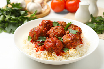 Delicious meatballs with rice, sauce and parsley on white table, closeup