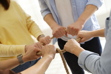 Fototapeta premium Unity concept. People holding rope together indoors, closeup