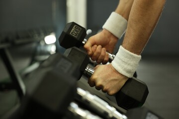 Athletic man training with dumbbells in gym, closeup