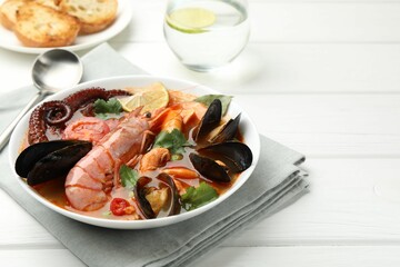 Delicious seafood soup served on white wooden table, closeup. Space for text