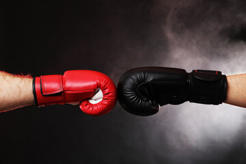Men in boxing gloves fighting on dark background with smoke, closeup
