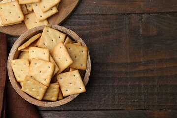 Tasty salty crackers on wooden table, top view. Space for text