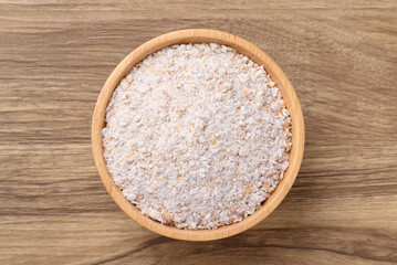 Whole wheat flour in bowl on wooden background, Table top view