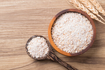 Whole wheat flour in bowl and spoon on wooden background, Table top view