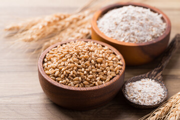 Wheat grain and whole wheat flour in bowl on wooden background