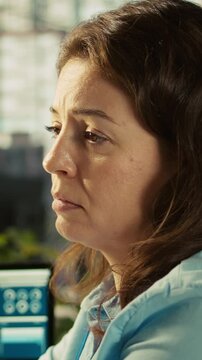 Vertical video Worker in office falling asleep at computer desk while analyzing business performance metrics. Exhausted woman dozing off while reviewing financial charts at work, camera B