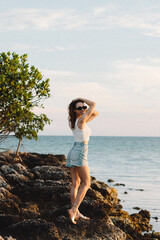 Young woman in blue jeans short at the beach. Beautiful colorful sunset at the beach. Summer vacation in Florida. Key West, Florida, US. Young lady is posing at the ocean on sunrise
