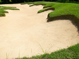 Empty golf bunker with smooth, patterned sand surface and surrounding green grass