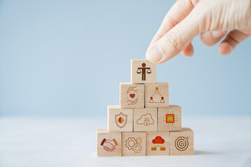 Hand holding wooden block with Ethical icons, business ethics and corporate compliance concept
