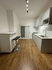 A modern minimalist kitchen design featuring beautiful natural elements throughout the space, set against a beautiful bay window overlooking the patio.