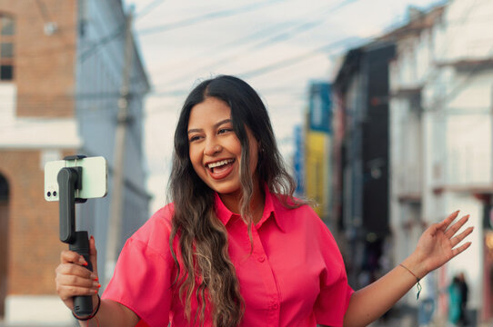A Young Woman is Capturing Moments with Her Smartphone Amid a Colorful Cityscape Environment