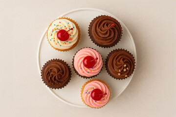 Top view of colorful cupcakes with cherries and frosting