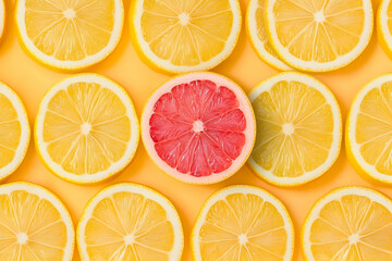 Obraz premium Colorful arrangement of lemon slices with a standout pink grapefruit in the center, perfect for summer freshness and healthy meals.