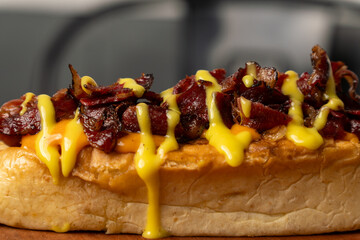 A hot dog topped with smoked beef and drizzled with honey mustard sauce, closed up