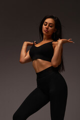 young woman posing in the hall. brunette in black suit doing exercises, healthy lifestyle. sport. beautiful figure