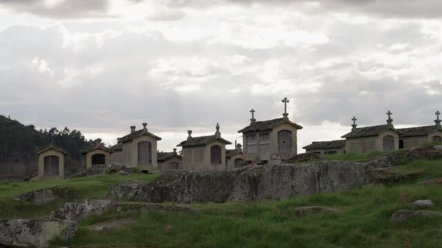 Granaries on stone platforms in Lindoso Portugal under dramatic cloudy sky