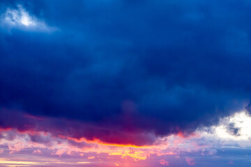 Spectacular sunset with dramatic sky. Dark storm clouds contrast with intense shades of pink, purple and orange on the horizon. Play of colors.