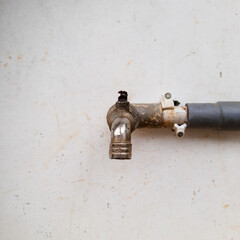 An old water faucet with a worn surface and slight damage bearing the marks of long-term use and outdoor elements