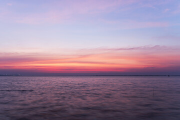 Beautiful sunrise or sunset over the sea, with colorful sky, soft clouds, and gentle waves.