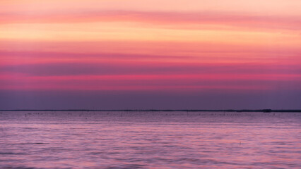 Beautiful sunrise or sunset over the sea, with colorful sky, soft clouds, and gentle waves.