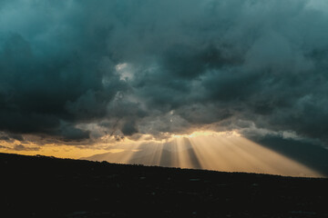 Dark stormy sky with sun rays breaking through, perfect for dramatic backgrounds, weatherthemed designs, and expressing hope during difficult times.