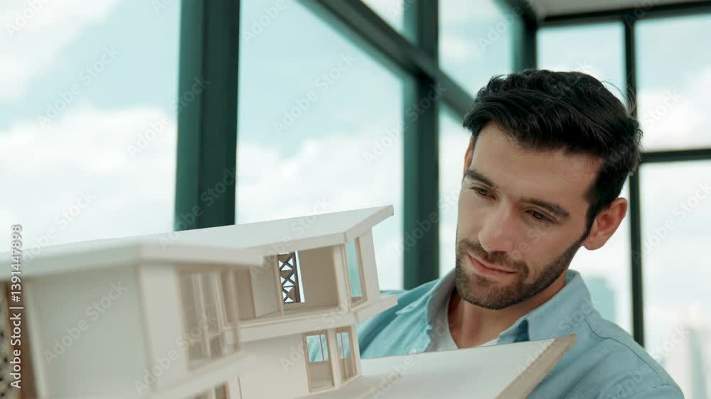 Aufkleber skilled smiling caucasian engineer turns house model left and right to check mistake point. professi