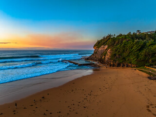 Sunrise at the beach with waves and a smattering of clouds