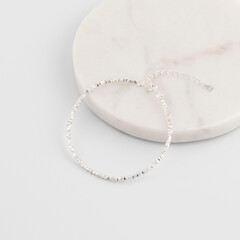 Minimalist silver chain bracelet on marble surface with adjustable clasp