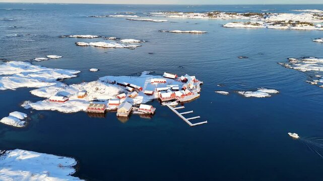 Aerial of a snow-covered small fishing village on the Haaholmen island at sunset in Averoy, Norway