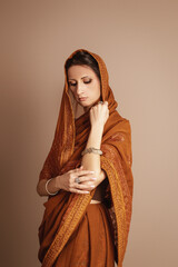 A beautiful young woman in traditional Indian attire, looking up. Selective focus, brown colors