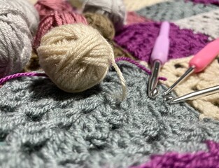 Crochet granny square, clews and hook on crochet blanket background photo