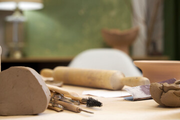 workshop table with pottery tools against green wall with lamp, home office concept