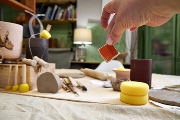 Close-up of a ceramic tile sample in hand against the background of a pottery workshop