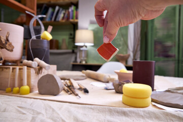 Close-up of a ceramic tile sample in hand against the background of a pottery workshop