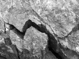 Big, deep, winding crack, crevice in black basalt rock. Destruction, split. Black and white photo....