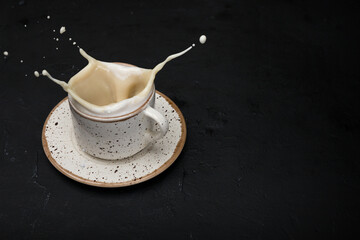 Coffee glass cup with splashes on a black background.